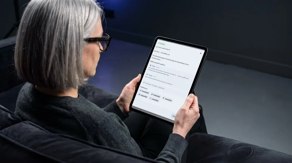 A creative director holding a tablet showing the SchedulifyX platform-specific captions screen.