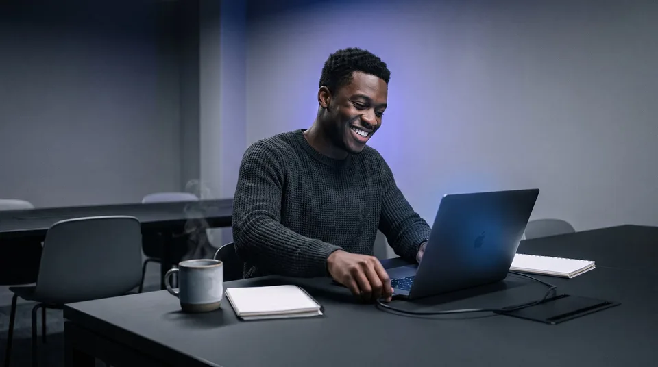 A marketing coordinator smiles while setting up his new SchedulifyX workspace on a laptop.